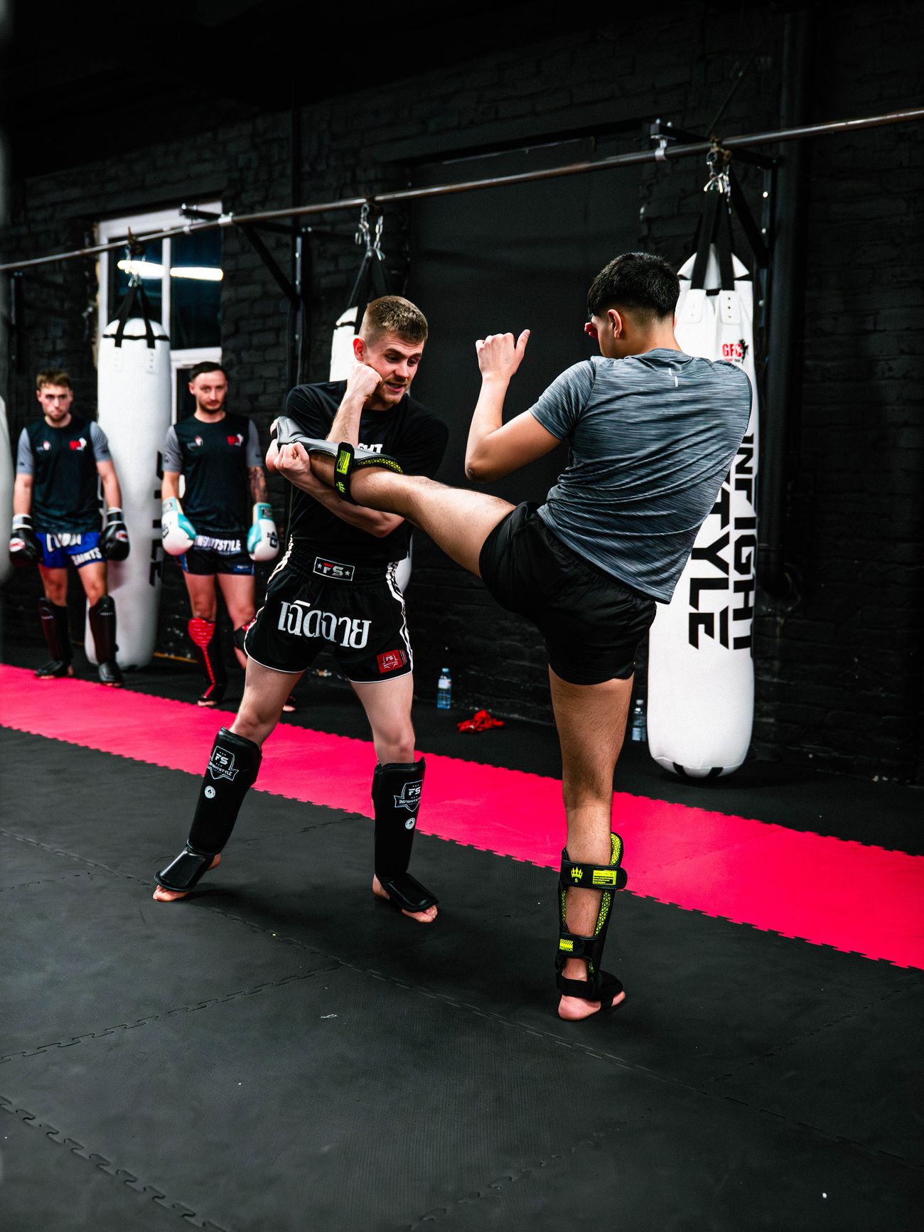 Luke Phillips catches a student's push kick while coaching Muay Thai technique