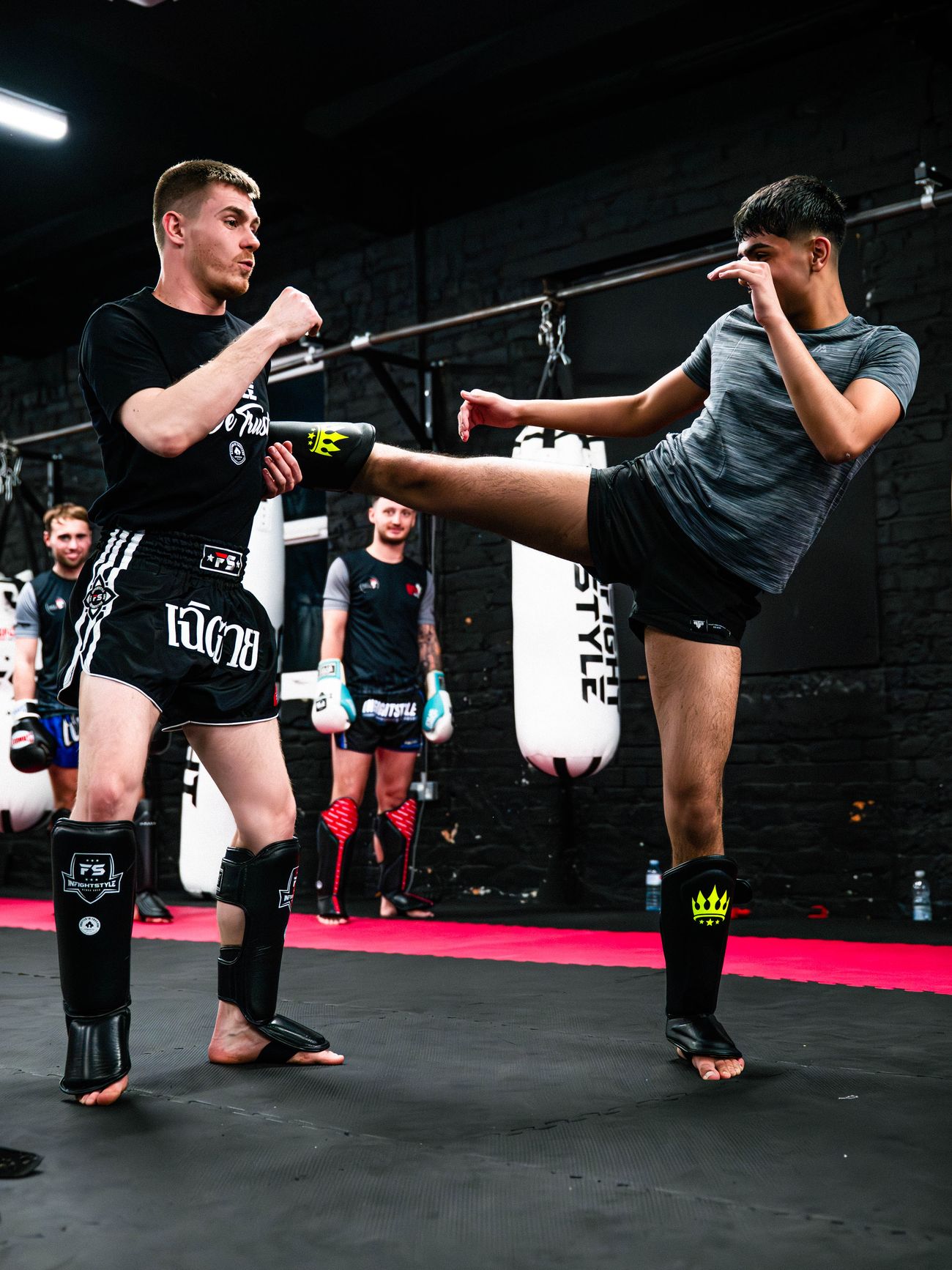 Luke Phillips holds a student's foot while coaching push-kick technique