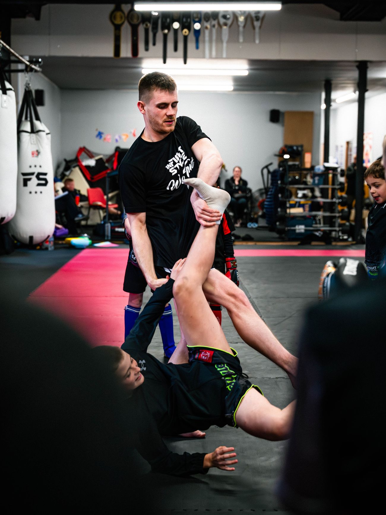 Luke Phillips helps a junior student through a floor stretching exercise during class