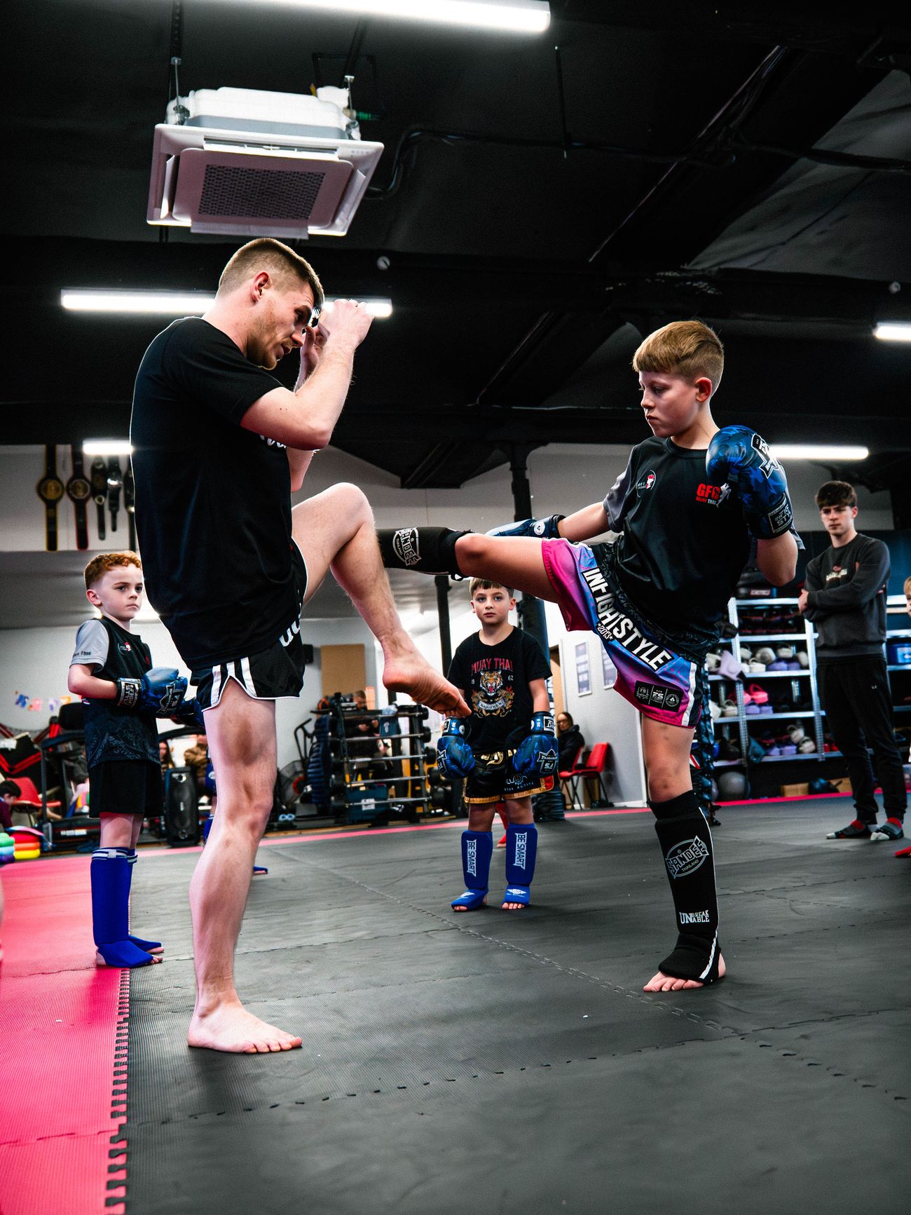 Luke Phillips demonstrates a knee drill with a young student during a children's Muay Thai class