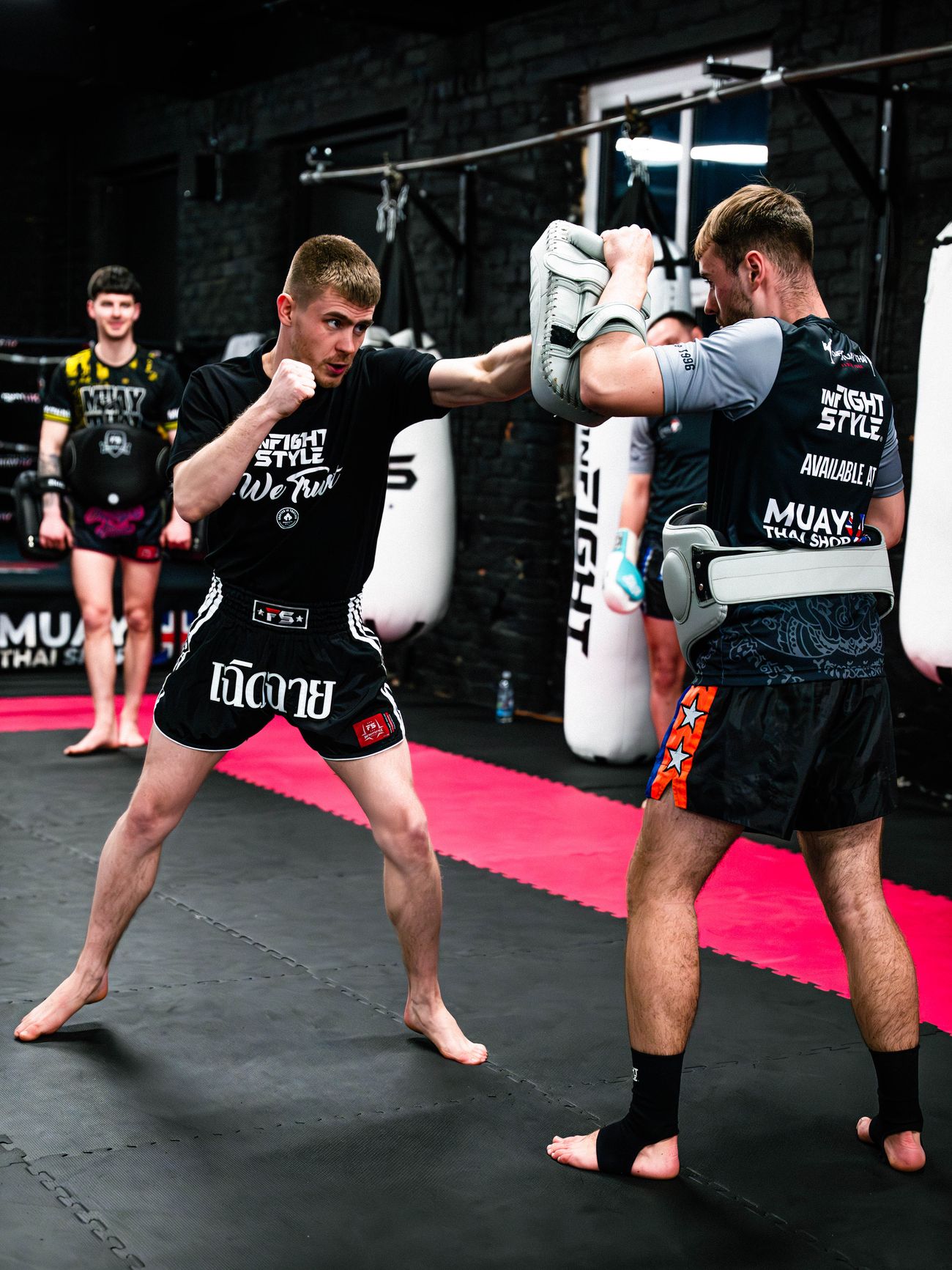 Luke Phillips throws a straight punch into pads held by a training partner