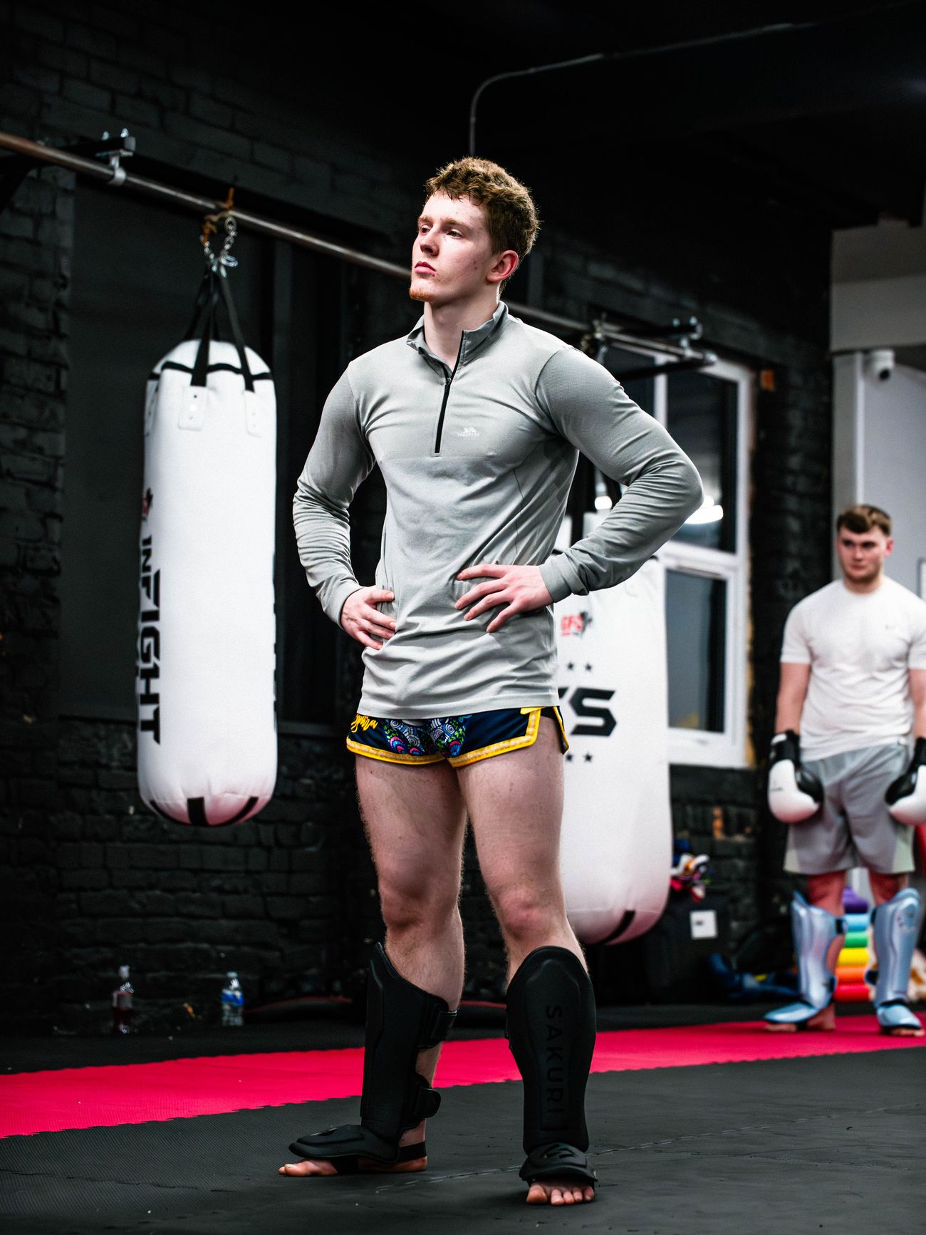 A Muay Thai student catching his breath between drills beside the GFC heavy bags